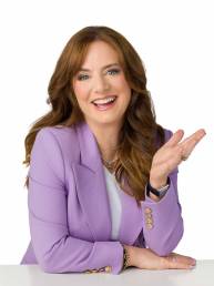An executive portrait of a red haired woman wearing a lavender blazer with an excited and happy expression.