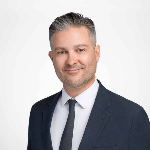 A corporate headshot of a male Denver, Colorado non-profit Executive Director with a subdued smile.