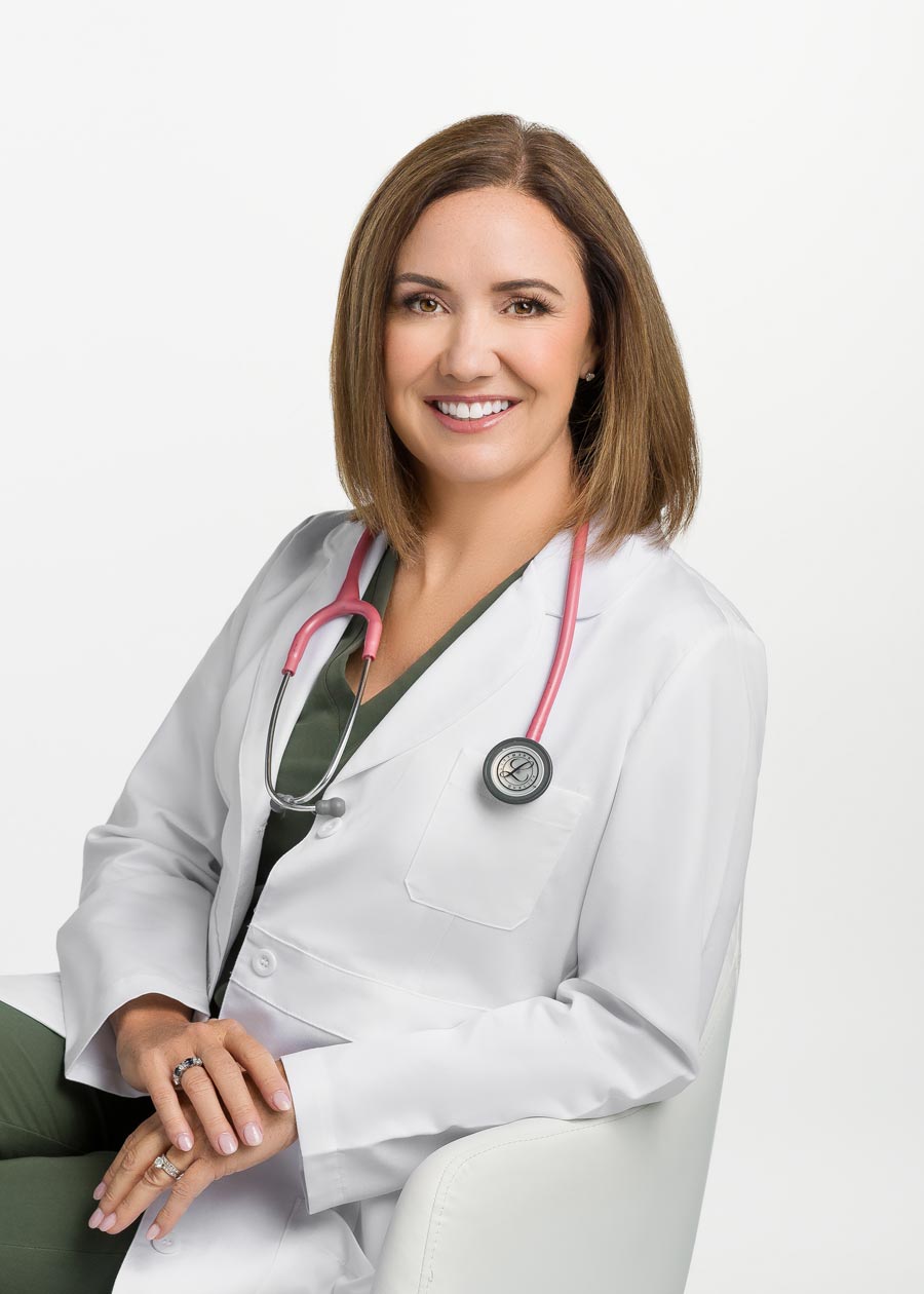 A physician sits confidently wearing a lab coat and stethoscope