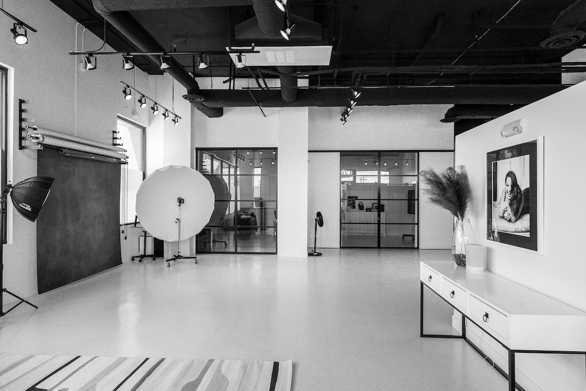 A spacious commercial portrait studio with black ceiling and white walls.