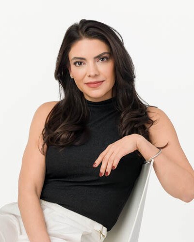A headshot of a brunette female sitting relaxed in a chair looking confident and in control