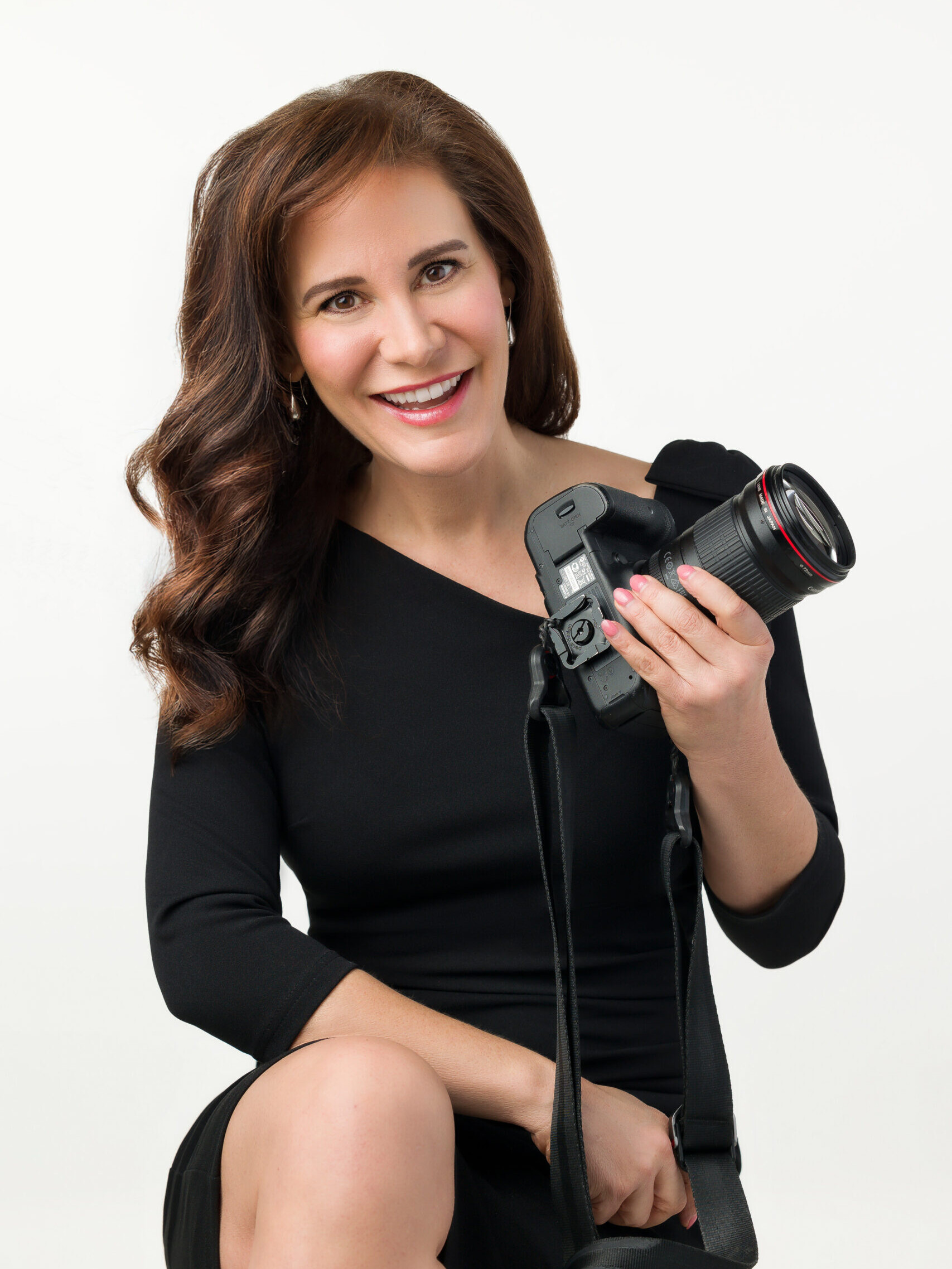 A smiling portrait of award-winning business headshot and personal branding portrait photographer, Rachel Sorbet, holding a camera.