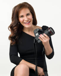 A smiling portrait of award-winning business headshot and personal branding portrait photographer, Rachel Sorbet, holding a camera.