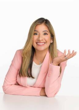 A real estate agent with an excited face holding her palm up and smiling for her branding photoshoot