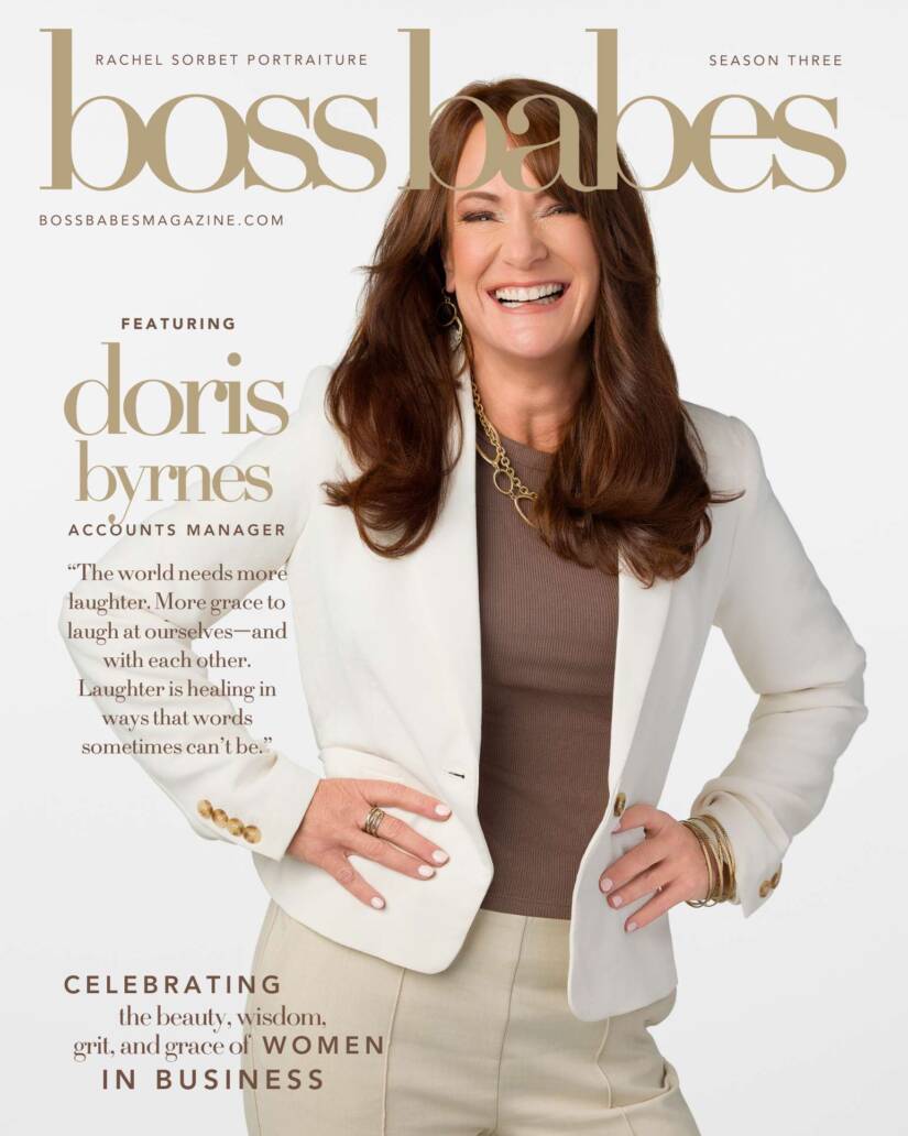 A photo of Doris Brynes on the cover of Boss Babes Magazine wearing a white blazer and laughing looking at the camera