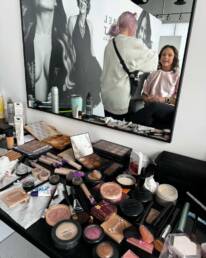 A behind the scenes look at a client receiving professional hair and makeup styling at the photo studio
