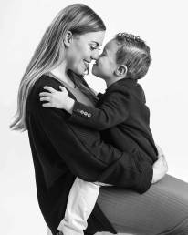 A mom sitting sideways with her 4 year old son facing her in her lap as they touch noses