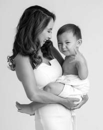 A young mother with long hair hold her toddler who is wearing a diaper cover