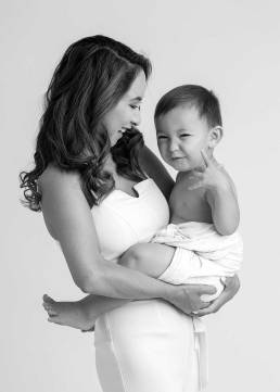 A young mother with long hair hold her toddler who is wearing a diaper cover