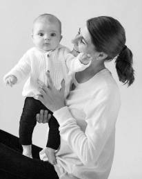 A mom sitting on the floor with her baby standing up in her lap