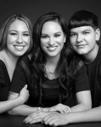 A mom of two teens sits at a table with her kids cuddled next to her