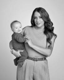 A corporate mom holds her baby on her hip